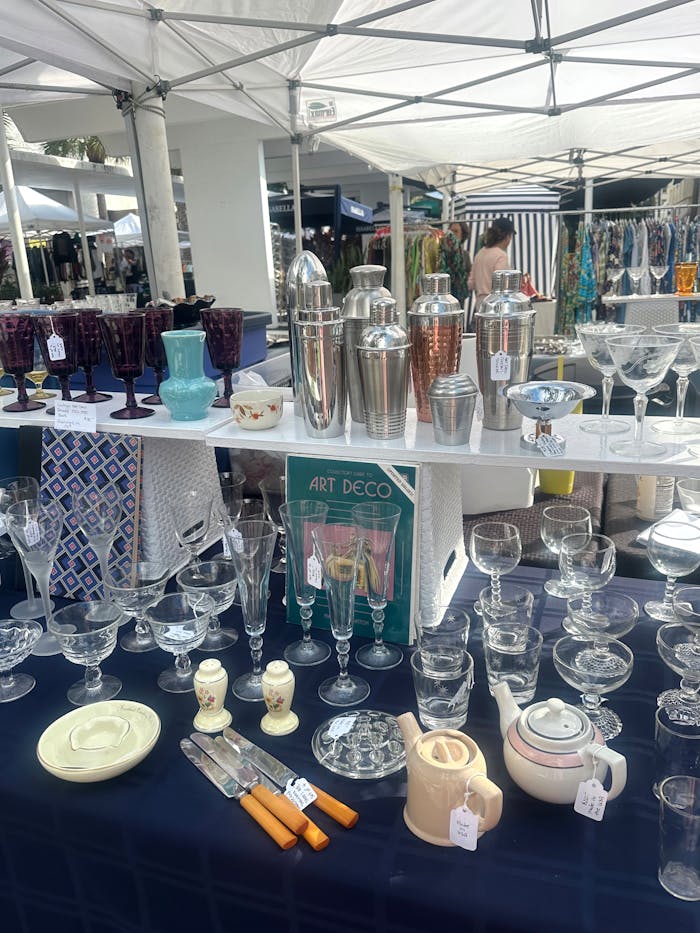 Art Deco style vintage glassware and barware displayed at an outdoor market table.